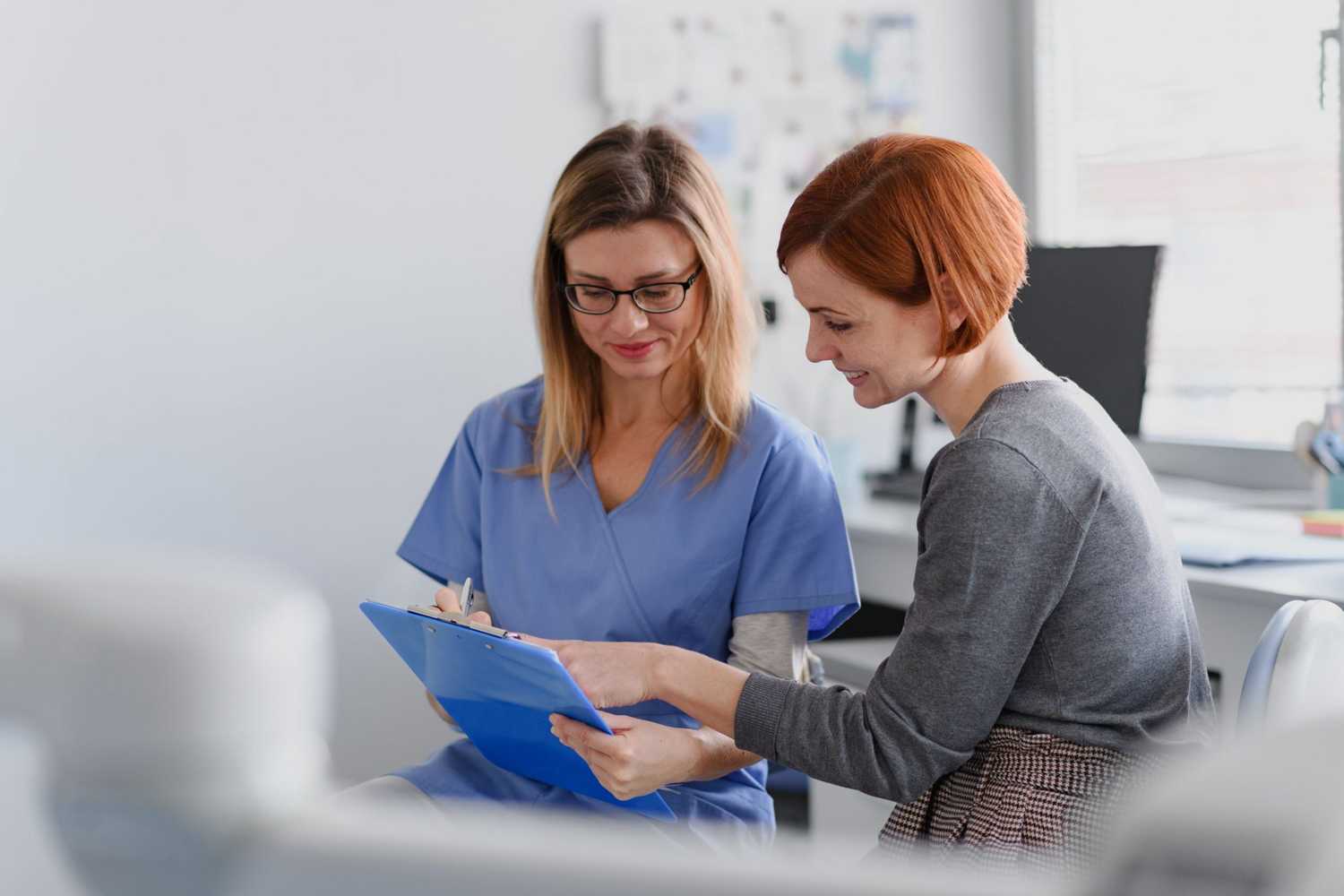 Female doctor consulting with a female patient, discussing test result in doctor office.