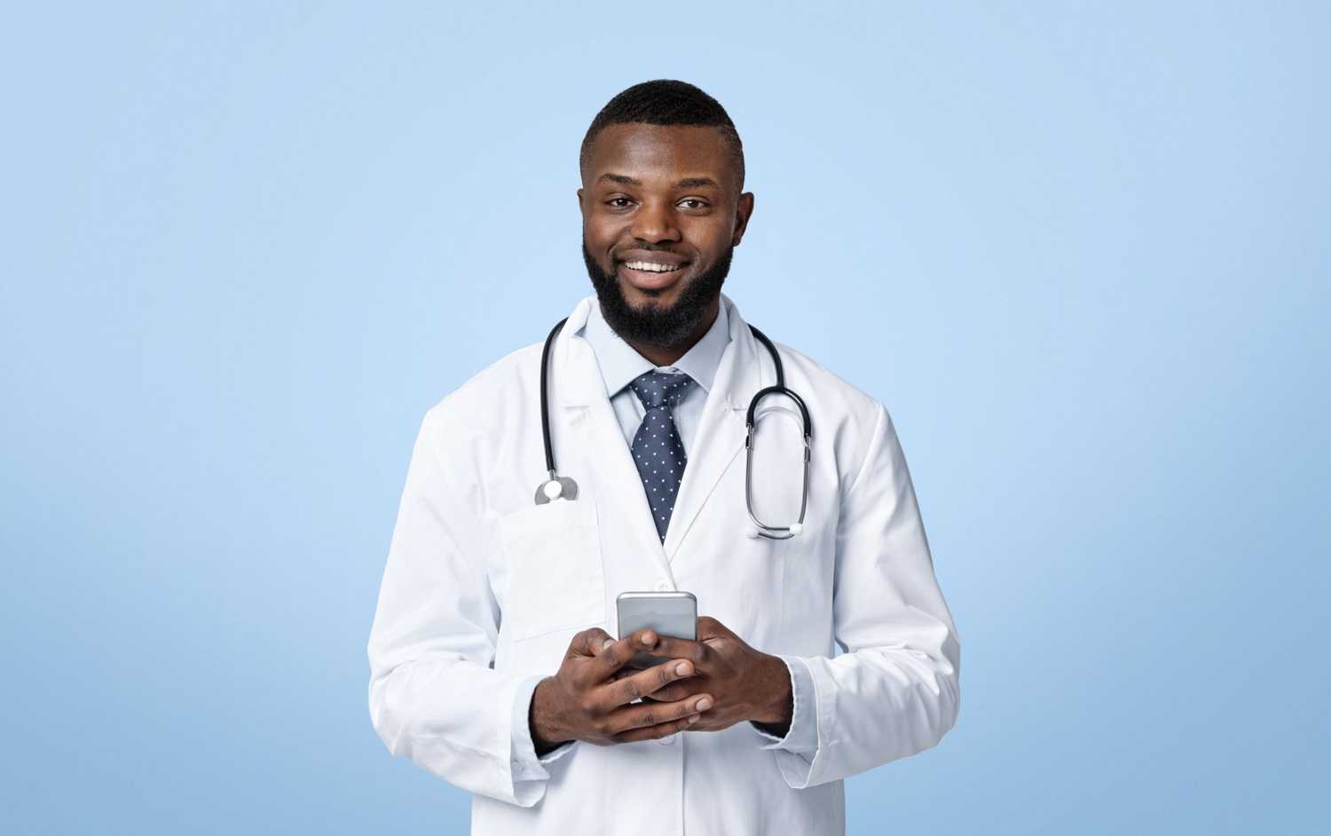 A young male CorVel telehealth doctor holding a smartphone on a virtual appointment with an injured worker.
